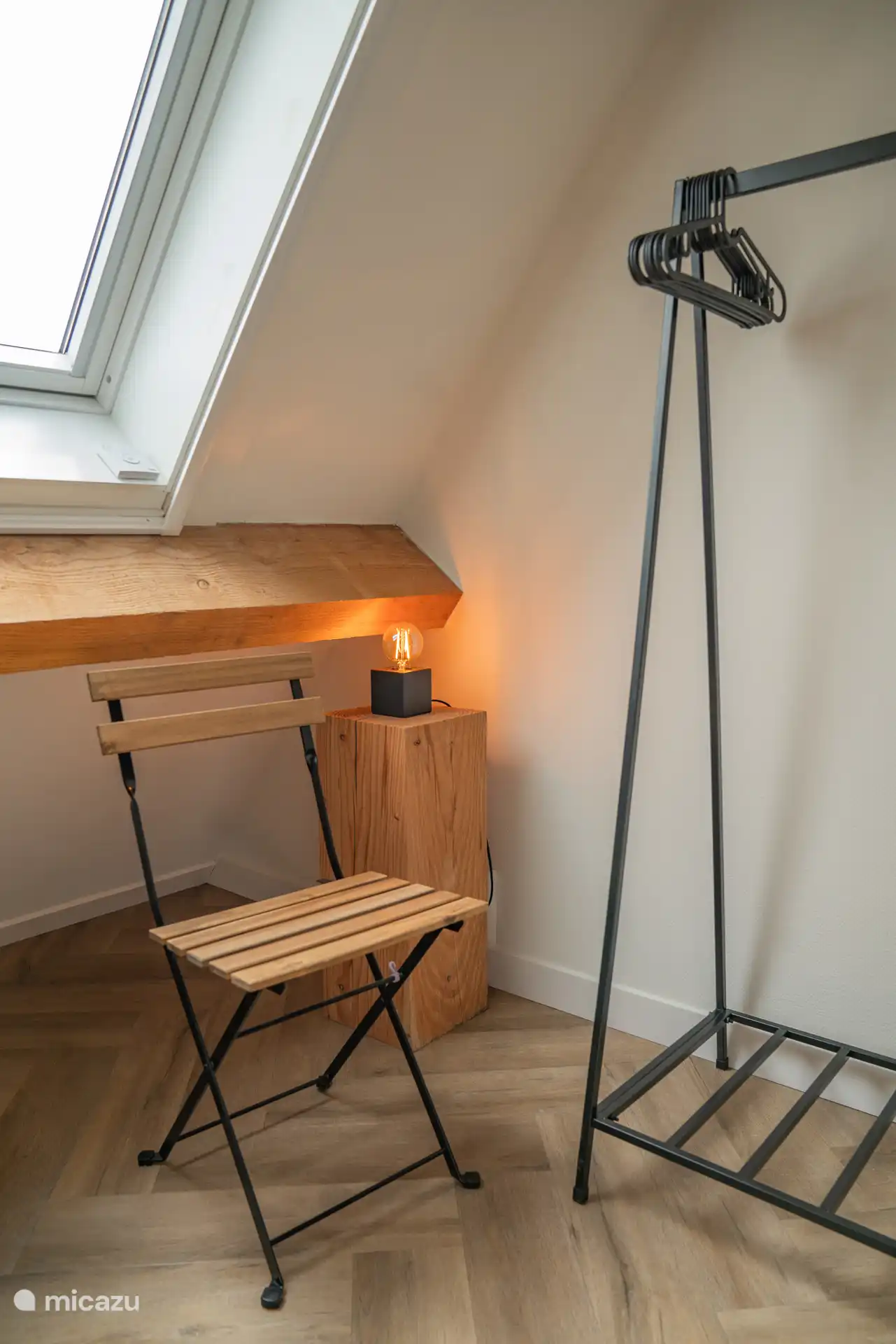 Dormitorio 1 con silla plegable y perchero.