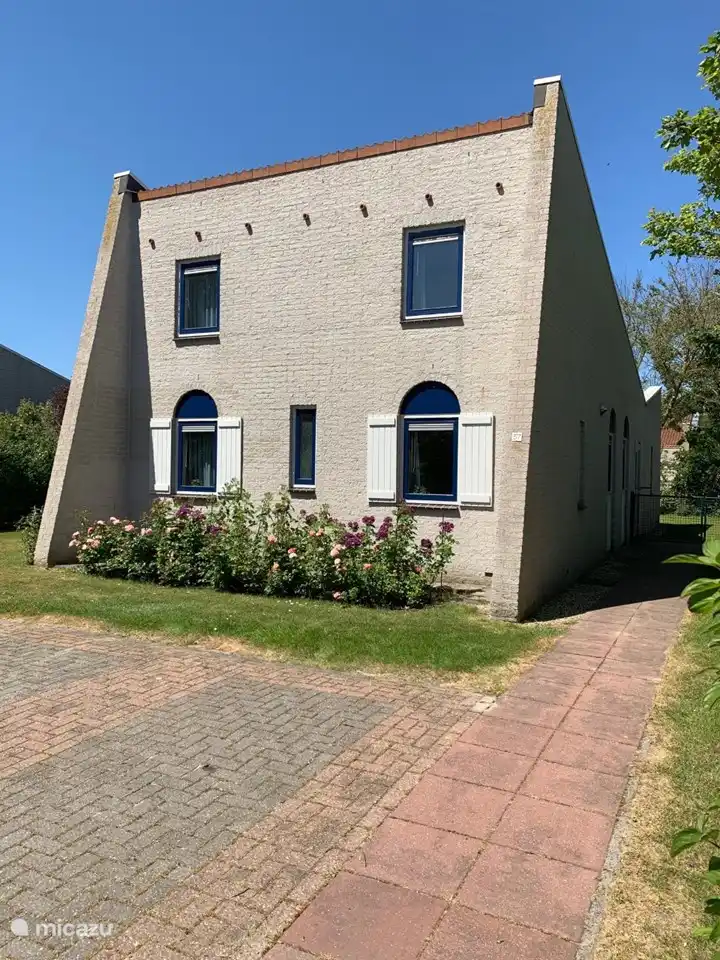 Voorzijde van het vakantiehuis met rozen en twee parkeerplaatsen