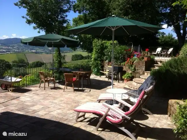 Twee terrassen met parasols en luie stoelen.
