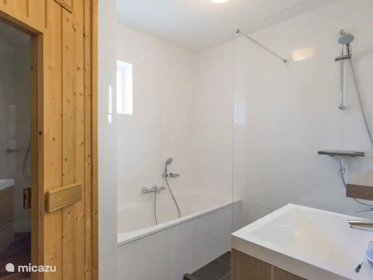 Gerenoveerde badkamer met een ligbad, inloopdouche, wastafel en sauna