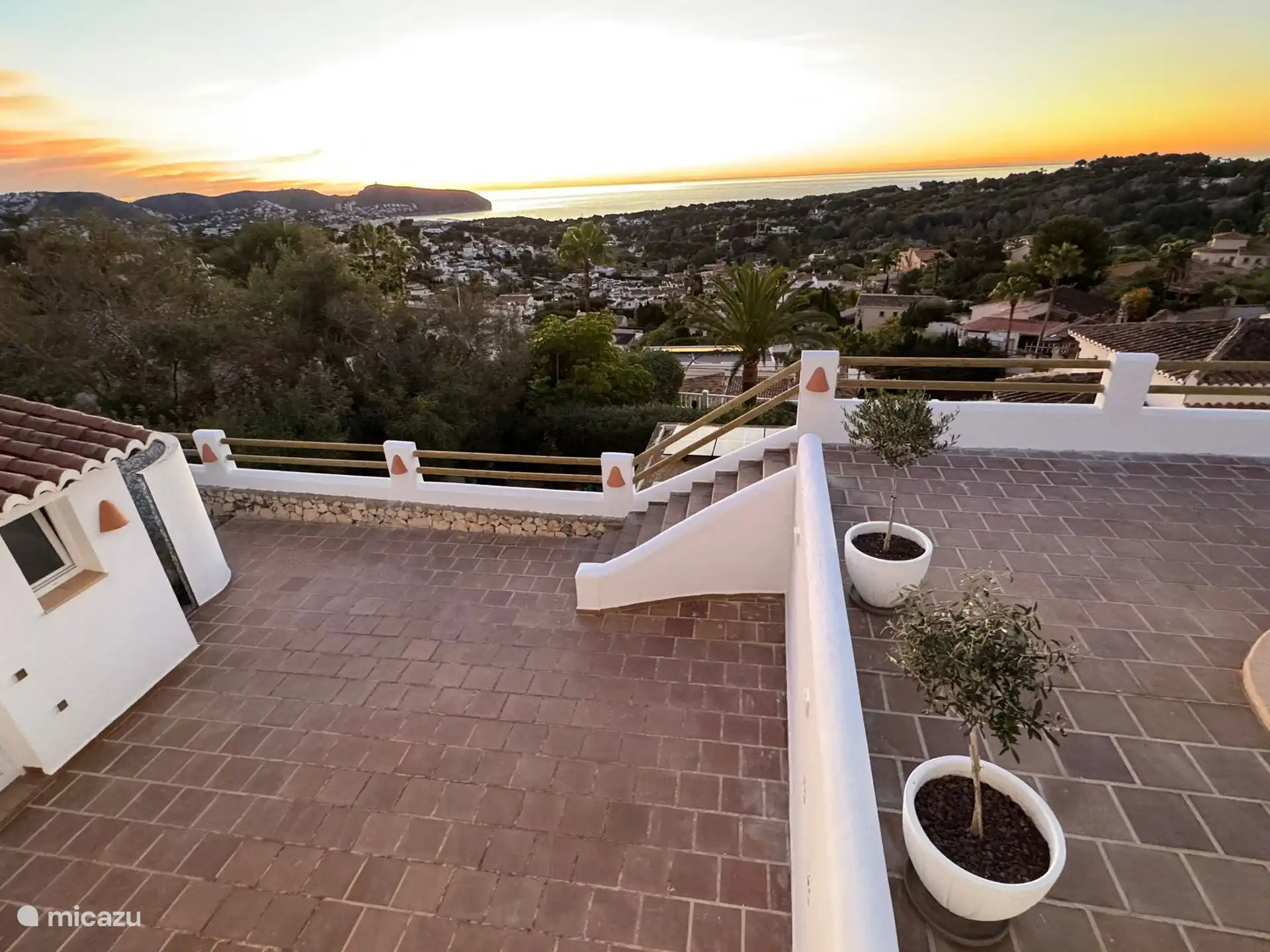 Het terras bij het zwembad met beneden de buitendouche en toilet