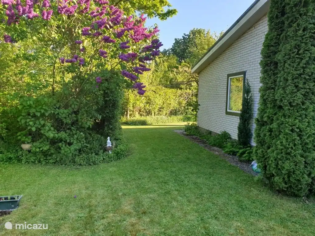 Freistehender Bungalow am Ende einer Sackgasse mit großem Garten mit Grün und Blumen rundherum und Parkplatz vor Ort