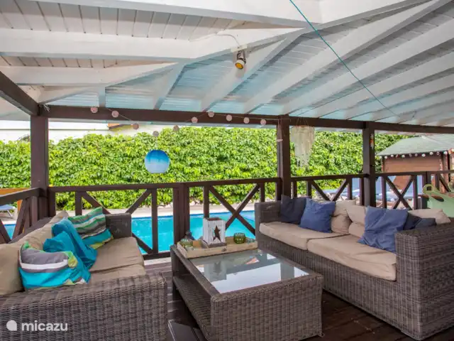 Location de Vacances Curaçao, Banda Ariba (est), Jan Thiel, maison de vacances - Kas Granjero La véranda, un endroit merveilleux pour vivre à l'extérieur. Derrière la véranda se trouve la piscine. C'est un endroit agréable pour manger à l'ombre, jouer à des jeux, se détendre ou lire un livre.