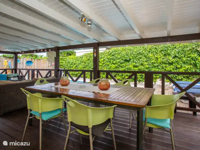 Location de Vacances Curaçao, Banda Ariba (est), Jan Thiel, maison de vacances - Kas Granjero La véranda, un endroit merveilleux pour vivre à l'extérieur. Derrière la véranda se trouve la piscine. C'est un endroit agréable pour manger à l'ombre, jouer à des jeux, se détendre ou lire un livre.