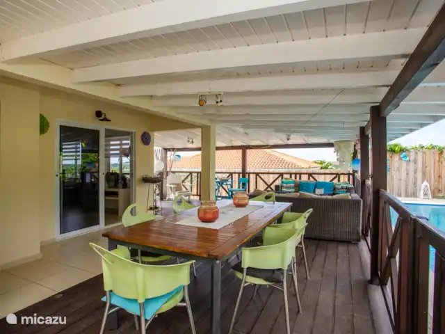 Location de Vacances Curaçao, Banda Ariba (est), Jan Thiel, maison de vacances - Kas Granjero La véranda, un endroit merveilleux pour vivre à l'extérieur. Derrière la véranda se trouve la piscine. C'est un endroit agréable pour manger à l'ombre, jouer à des jeux, se détendre ou lire un livre.