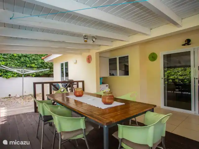 Location de Vacances Curaçao, Banda Ariba (est), Jan Thiel, maison de vacances - Kas Granjero La véranda, un endroit merveilleux pour vivre à l'extérieur. Derrière la véranda se trouve la piscine. C'est un endroit agréable pour manger à l'ombre, jouer à des jeux, se détendre ou lire un livre.