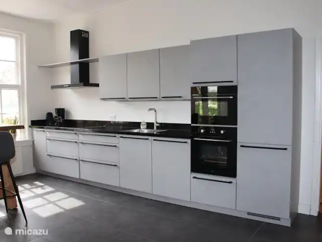 Granja de vacaciones De Steeg en Países Bajos, Güeldres, De Steeg - casa de campo La cocina con una estufa de 5 quemadores, un refrigerador grande, un lavavajillas, un horno y una combinación de microondas. Además, hay una mesa alta en la cocina donde puedes pararte o sentarte.