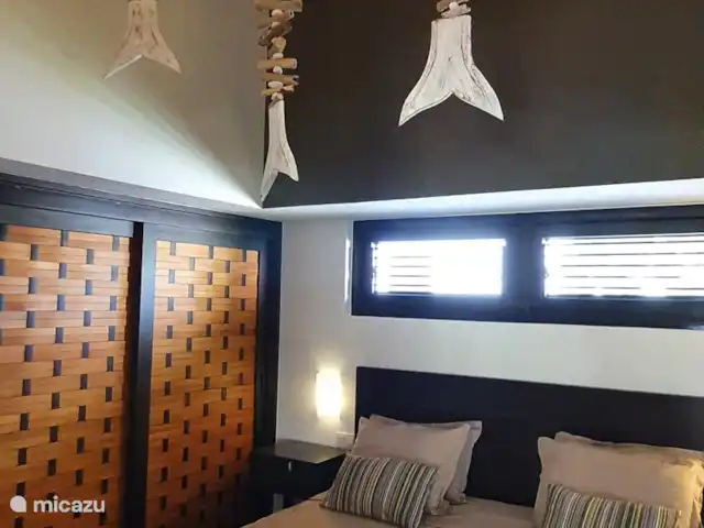 BlueBay Garden à la plage et à la piscine | Curaçao, Curaçao-Centre, Blue Bay - maison de vacances La chambre principale avec des poissons en bois flotté, suspendus au haut plafond.