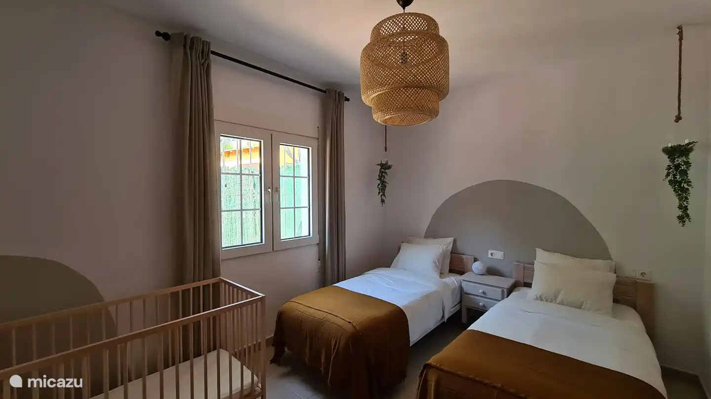 Slaapkamer met uitzicht op de Olta berg, voorzien van een kinderbedje,