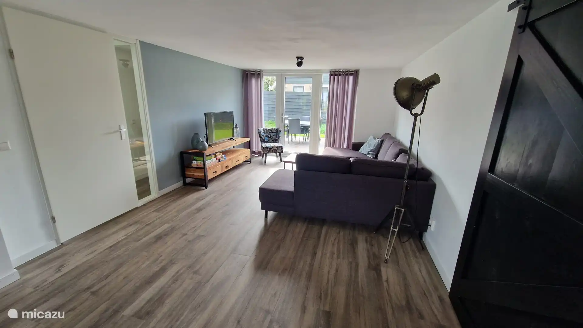 Wohnzimmer mit TV, geräumigem Sofa und Sitzecke. 