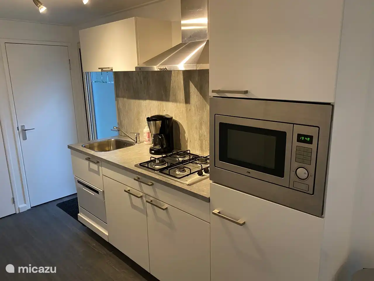 Cuisine avec réfrigérateur, congélateur, four combiné et lave-vaisselle.