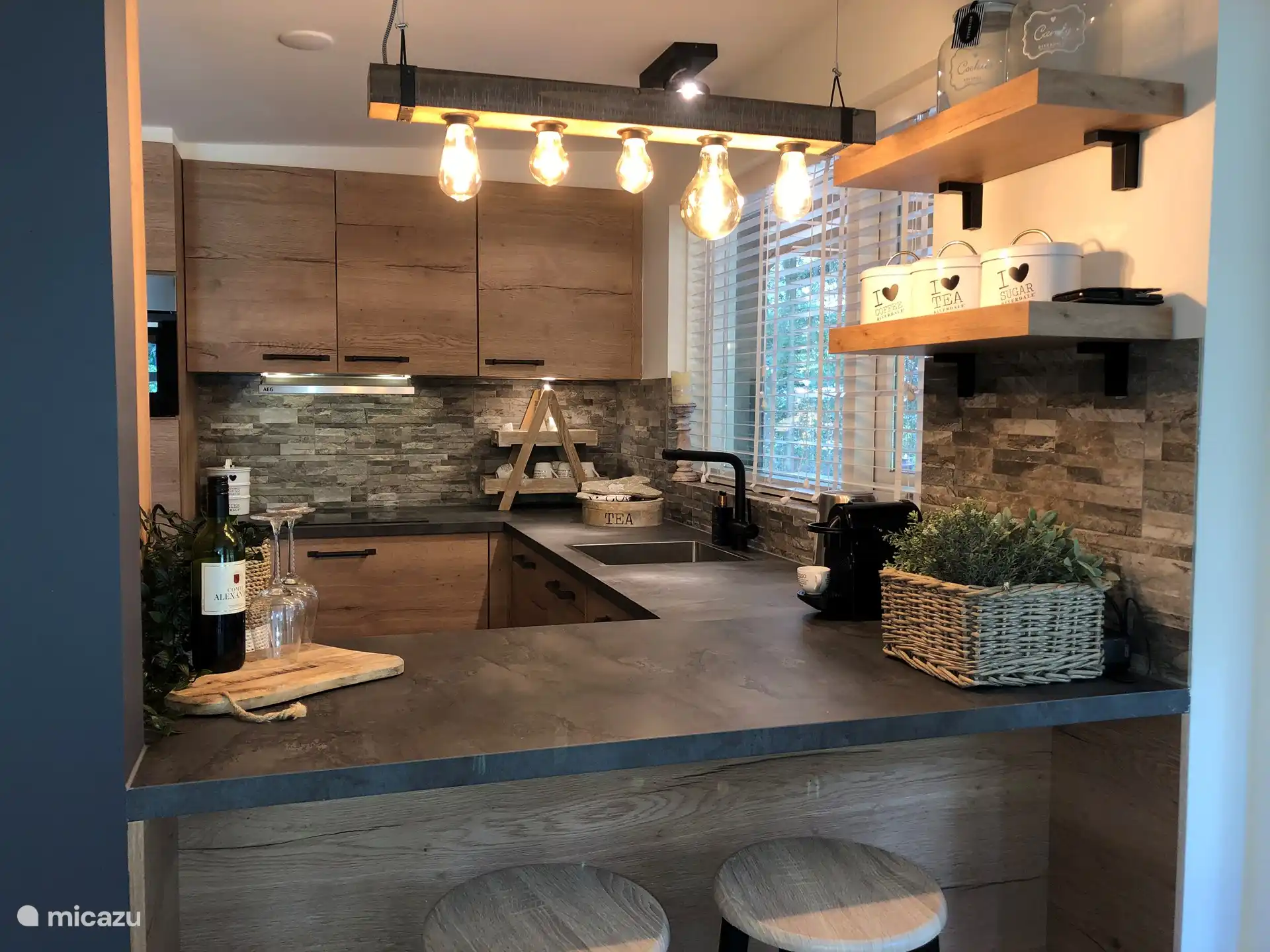 Vue du séjour sur la cuisine ouverte, bar avec deux tabourets