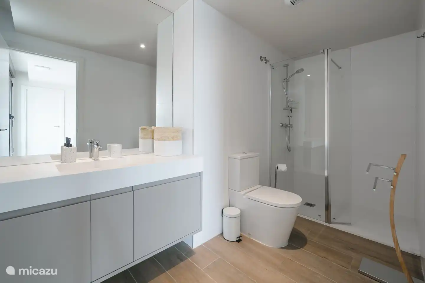Spacious, modern bathroom with walk-in shower, toilet and sink.