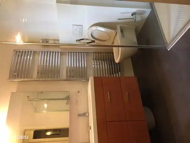 The bathroom with double sink and mirror cabinet, radiator, toilet and the shower on the right