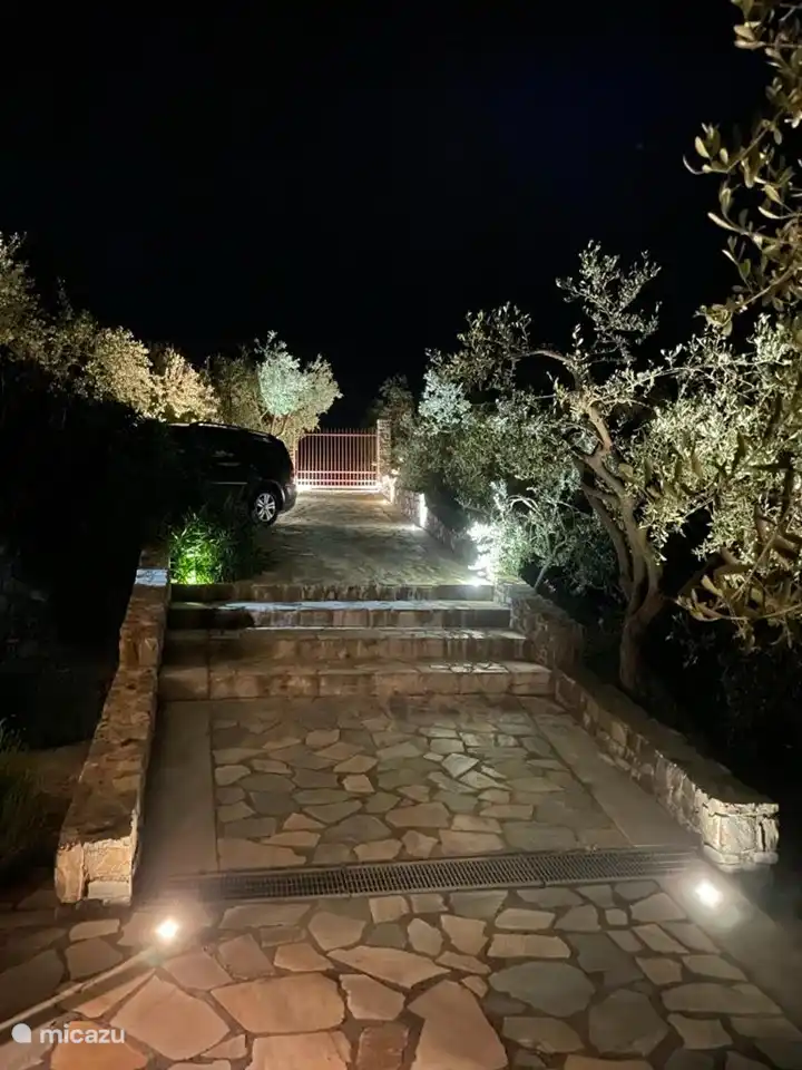 De villa is geheel omheind met een toegangspoort en hek en de tuin is sfeervol verlicht 