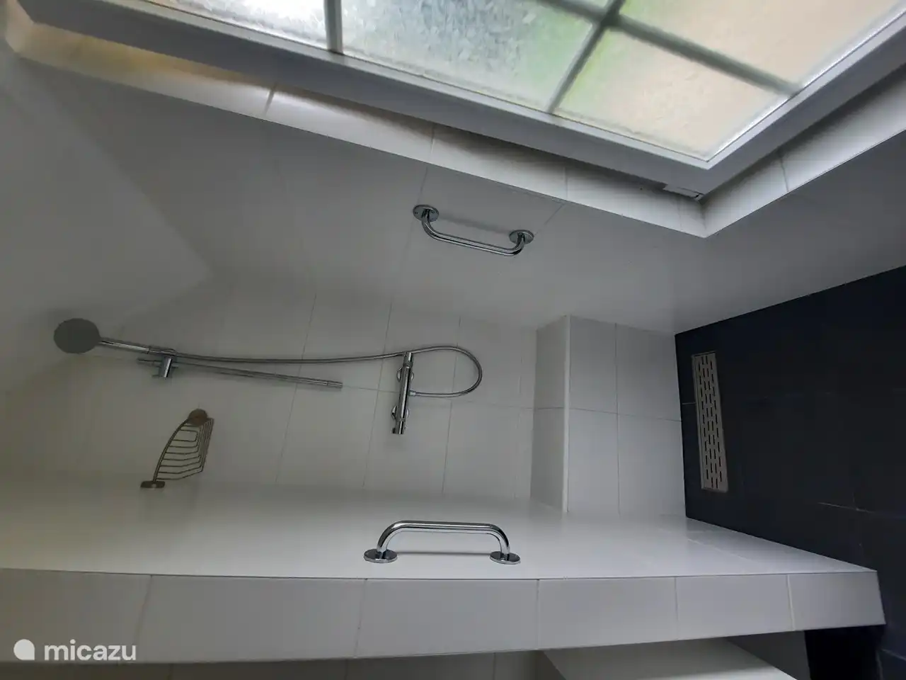 The shower is equipped with a grab bar and seat