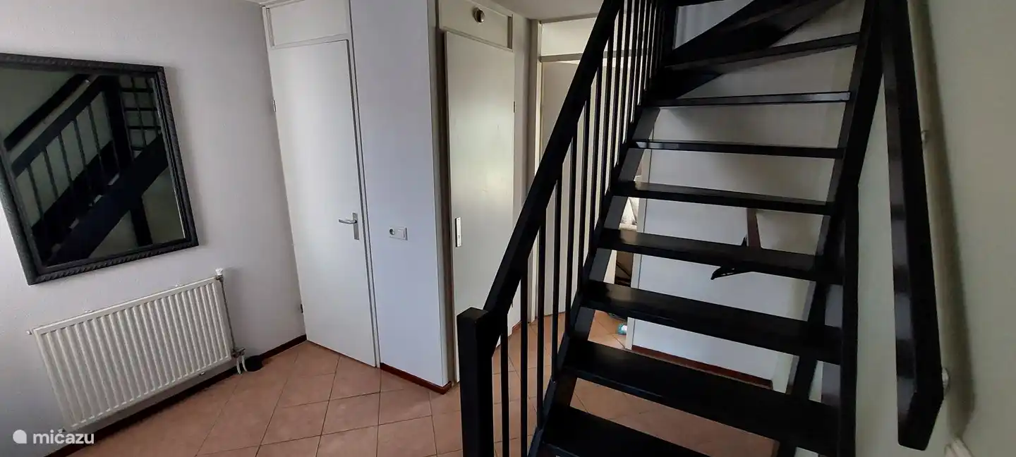 Dit is de ruime hal. Onder de trap kunt u de jassen ophangen. 