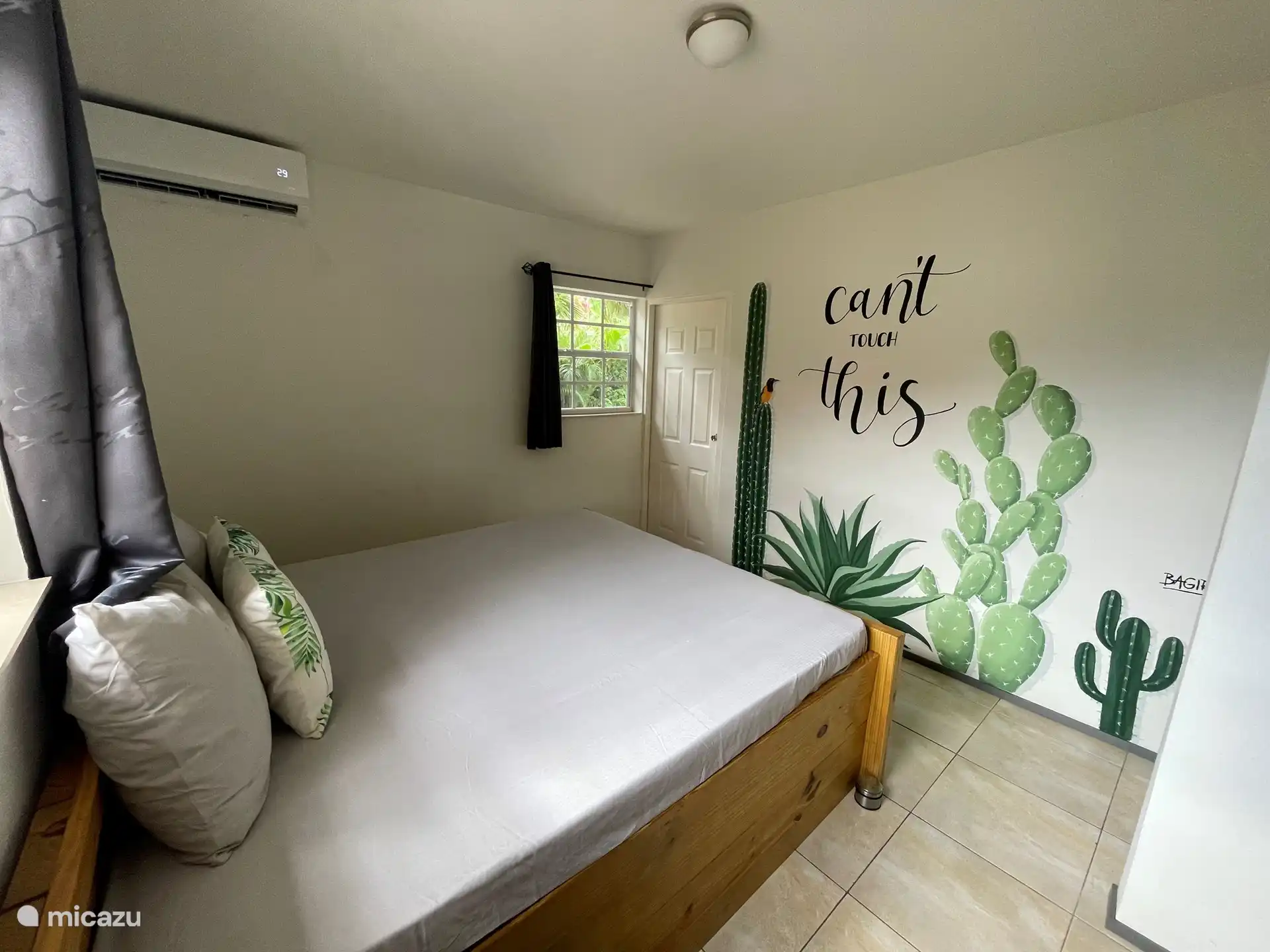 Bedroom 1 with air conditioning and a beautiful mural made by a local artist.