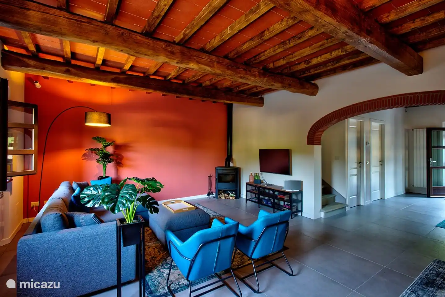 Das Wohnzimmer mit großem Sofa, Holzofen und Flachbildfernseher