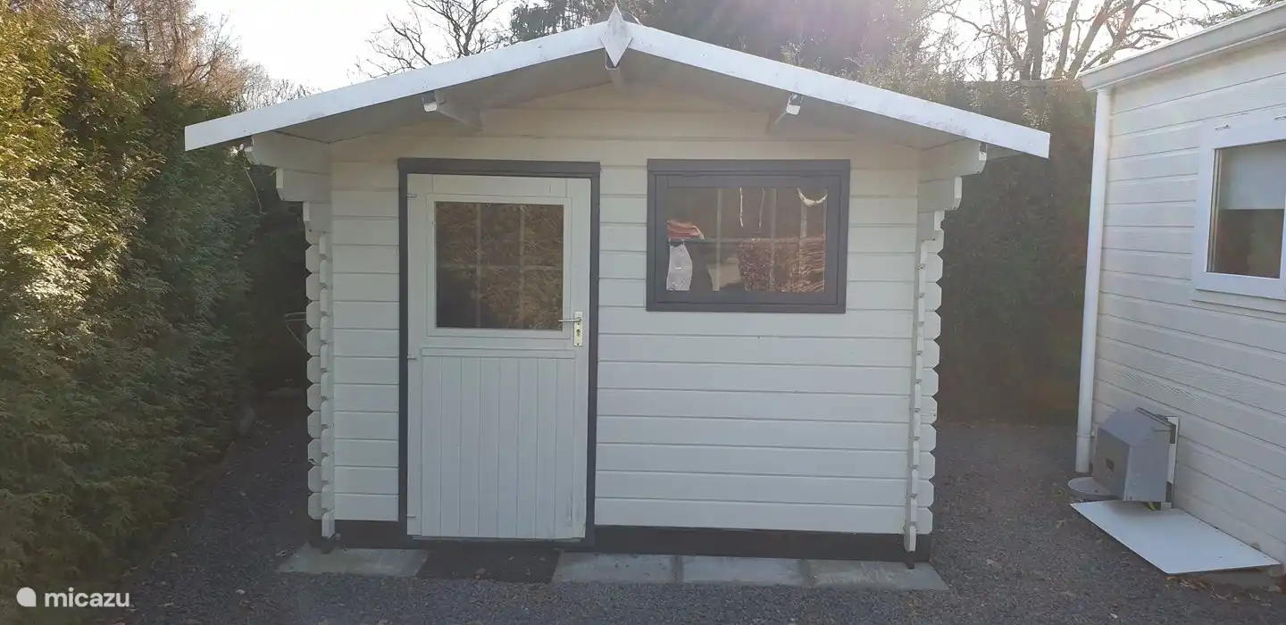 Der hölzerne Abstellraum mit Gefrierschrank, Geschirrspüler und Waschmaschine. Es ist genug Platz für zwei Fahrräder.