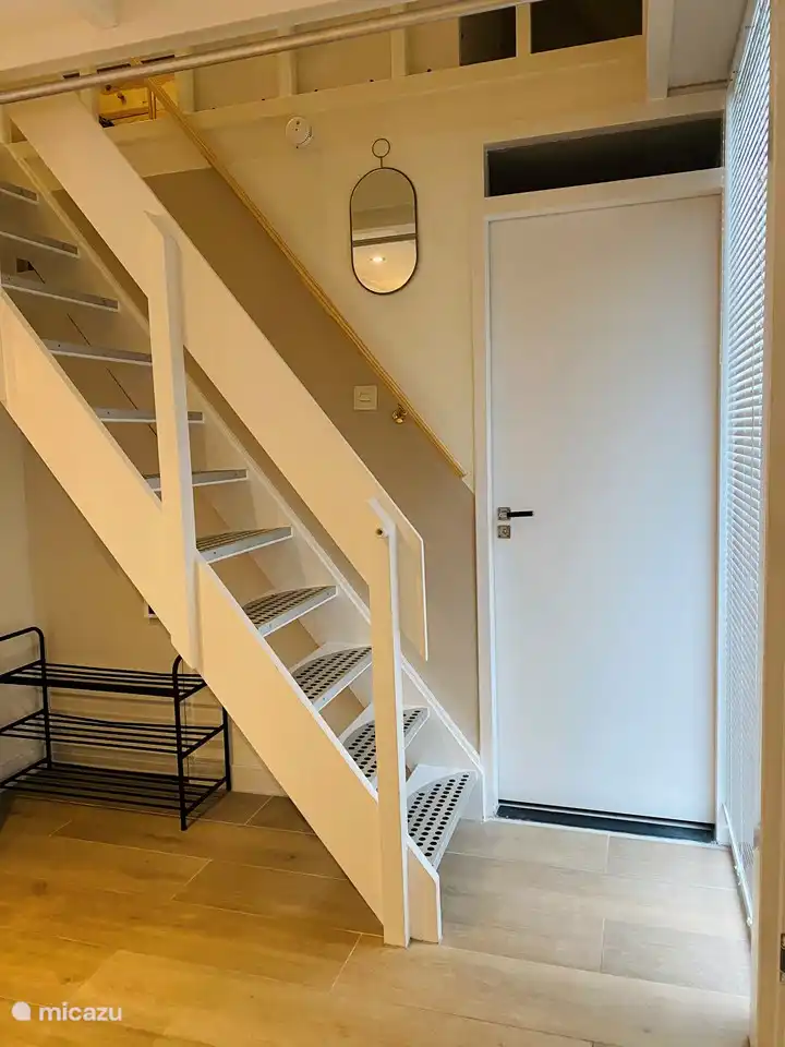 Treppe mit Armlehnen auf beiden Seiten. Die Tür bietet Zugang zum Bad und zur Toilette.