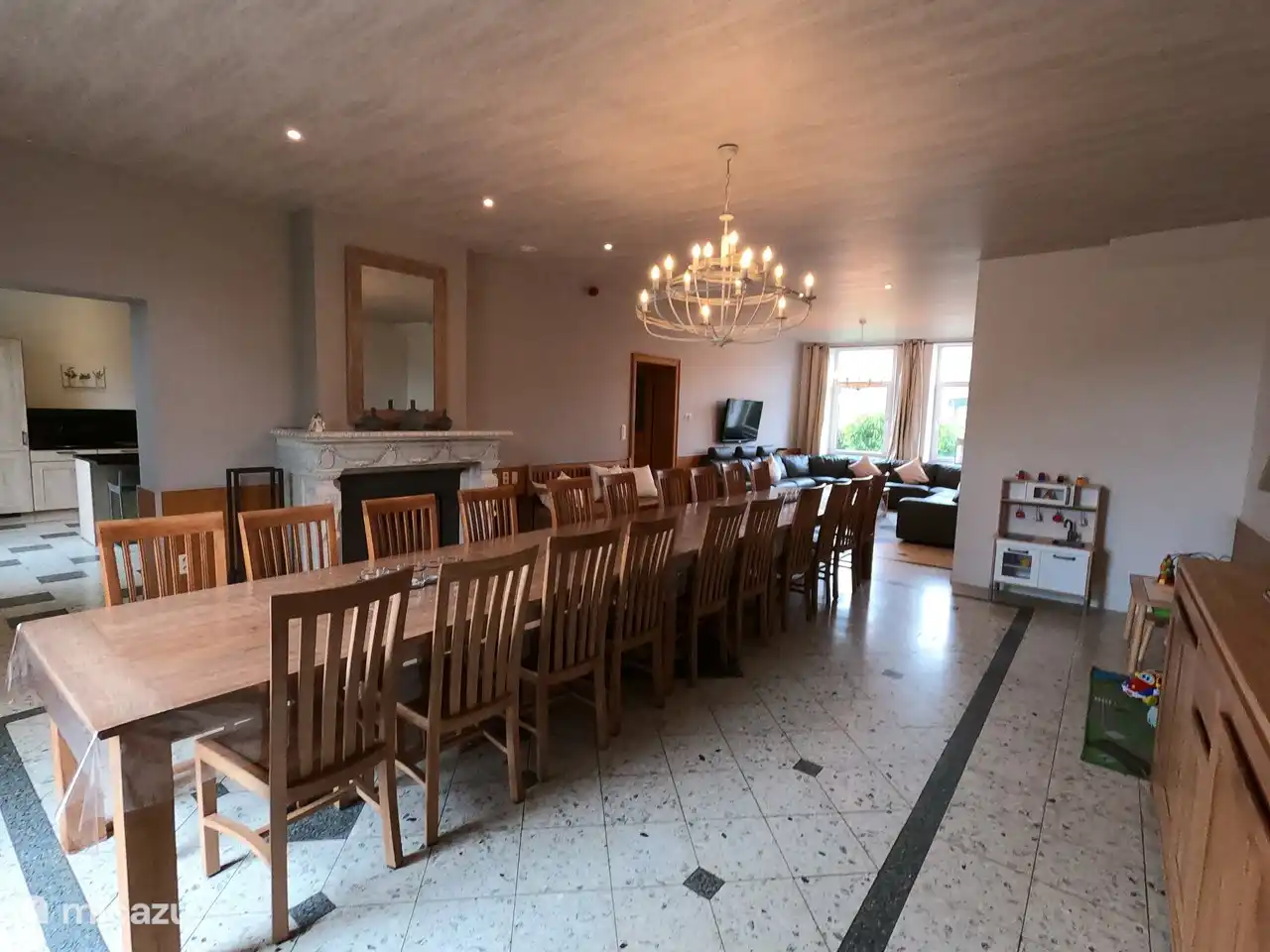 Coin repas juste à côté de la cuisine avec 20 chaises et foyer chaleureux