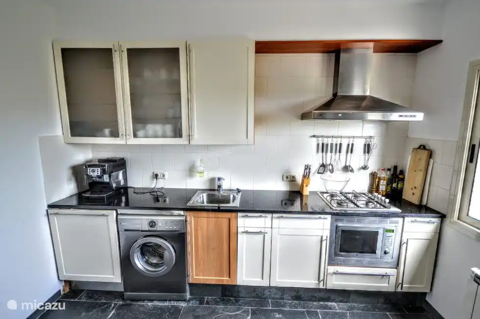 Cuisine avec lave-vaisselle, lave-linge, réfrigérateur/congélateur, machine à expresso et four micro-ondes combiné.