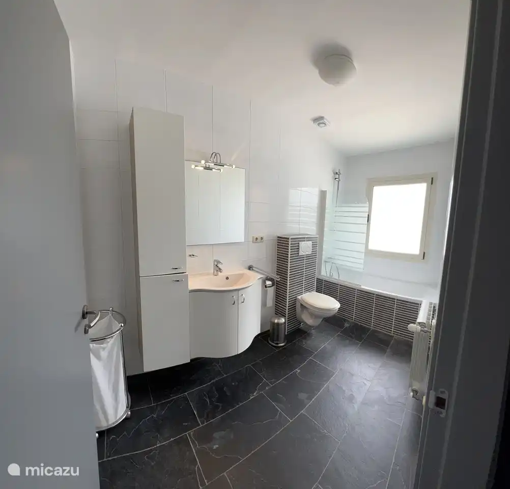 Salle de bain à l'étage avec baignoire/douche, toilette et meuble vasque.