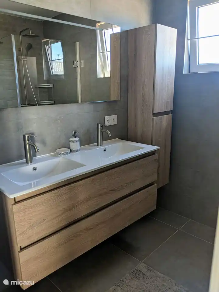 Zweites Badezimmer mit Waschbecken, Regendusche und WC.