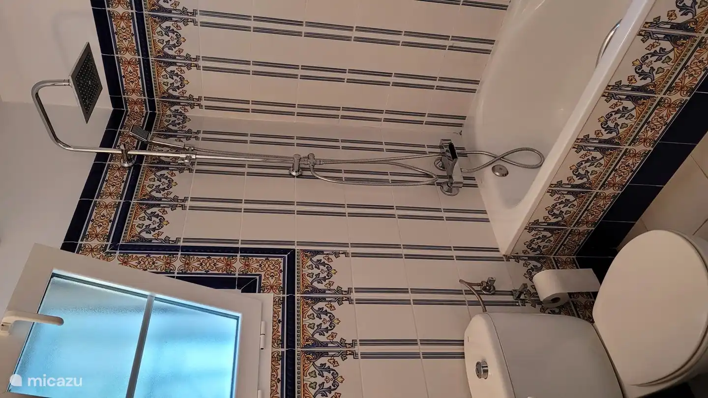 Geräumiges Badezimmer im andalusischen Stil mit WC, Waschbecken, Badewanne und Regendusche.