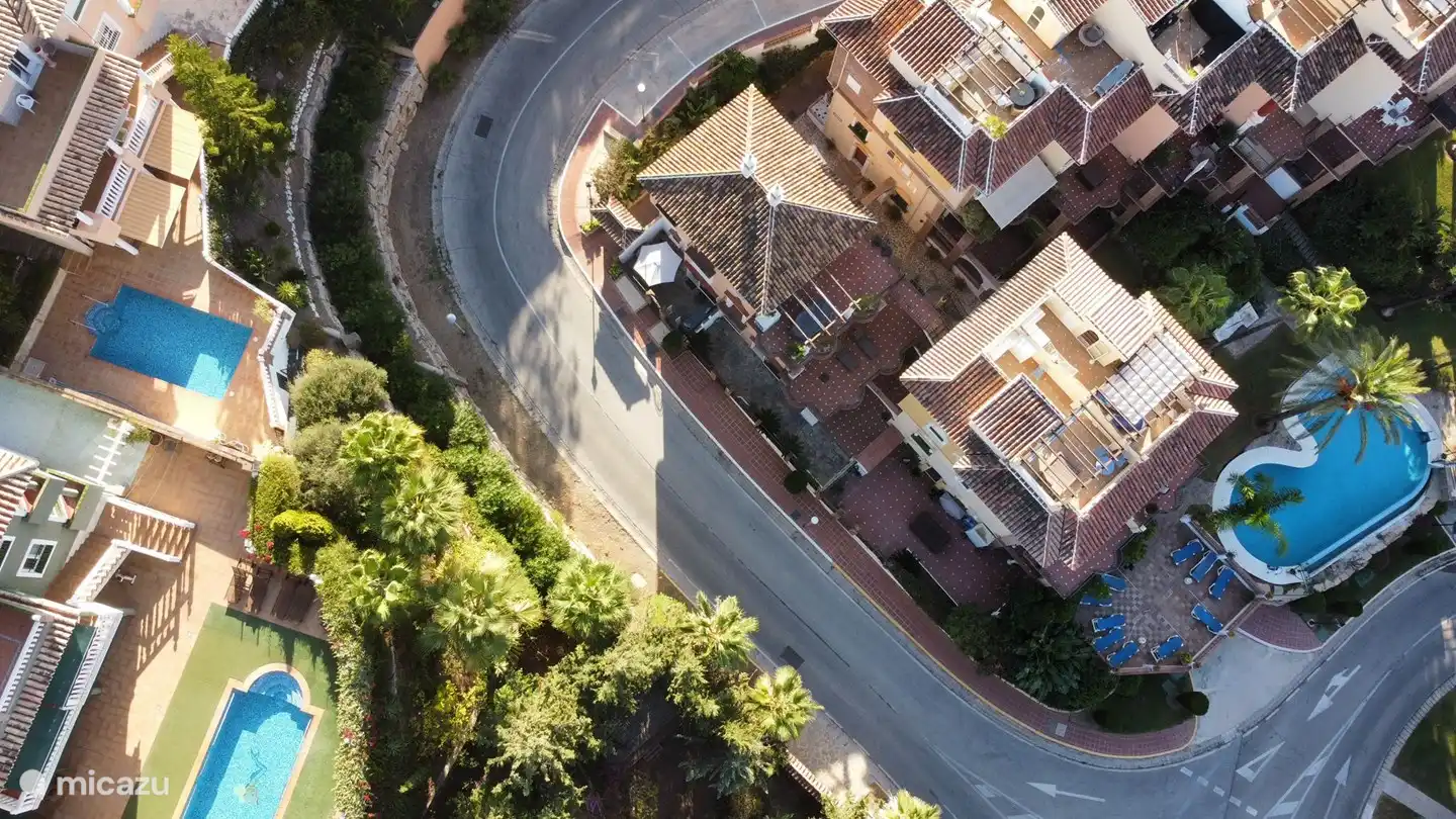 Von oben gesehen: Nur 15 Meter vom Pool entfernt. Links im Foto der weiße Sonnenschirm der Terrasse vorne. Rechts das Schwimmbad mit Garten und Palmen
