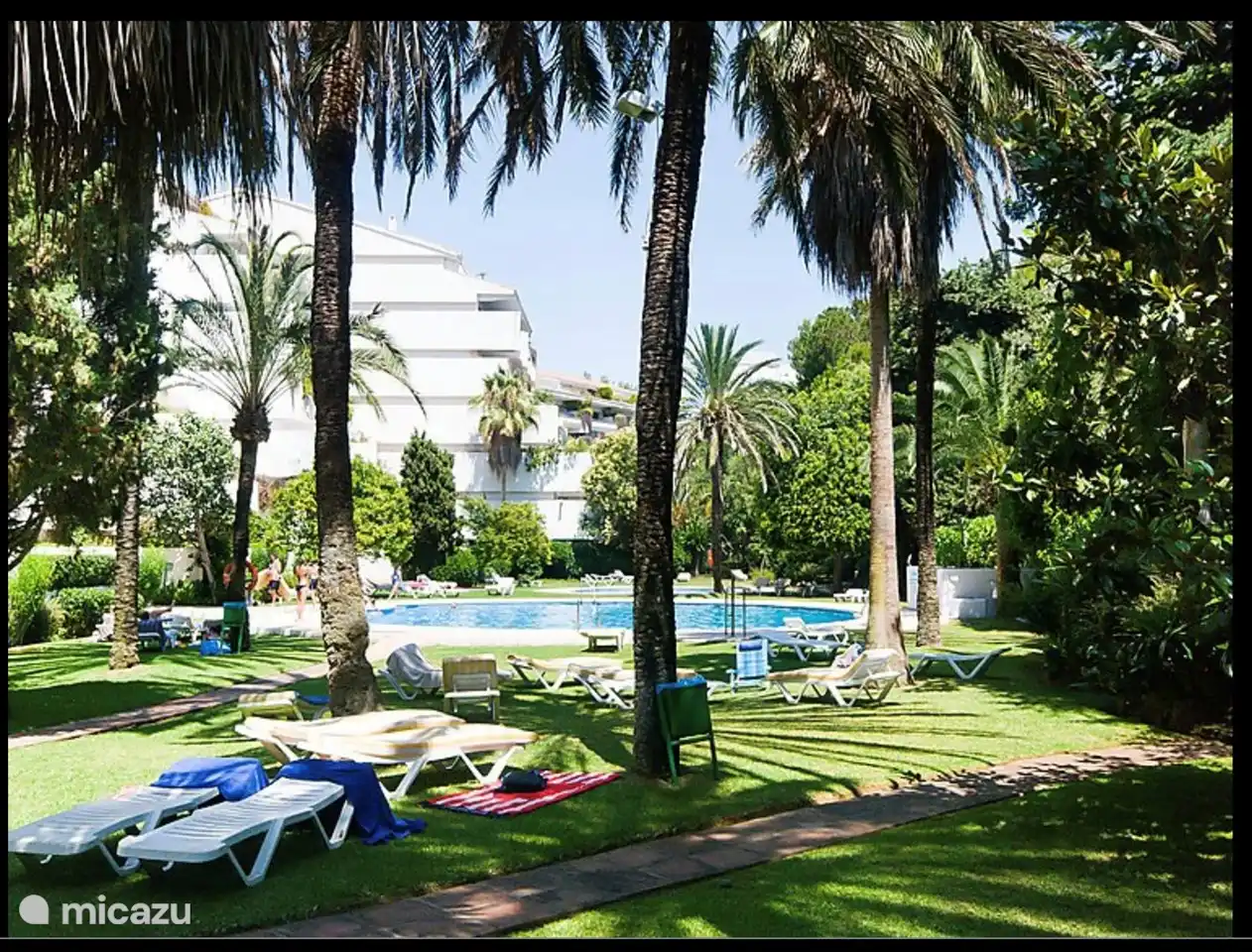 Jardin magnifiquement envahi d'un complexe d'appartements avec piscine et chaises longues.