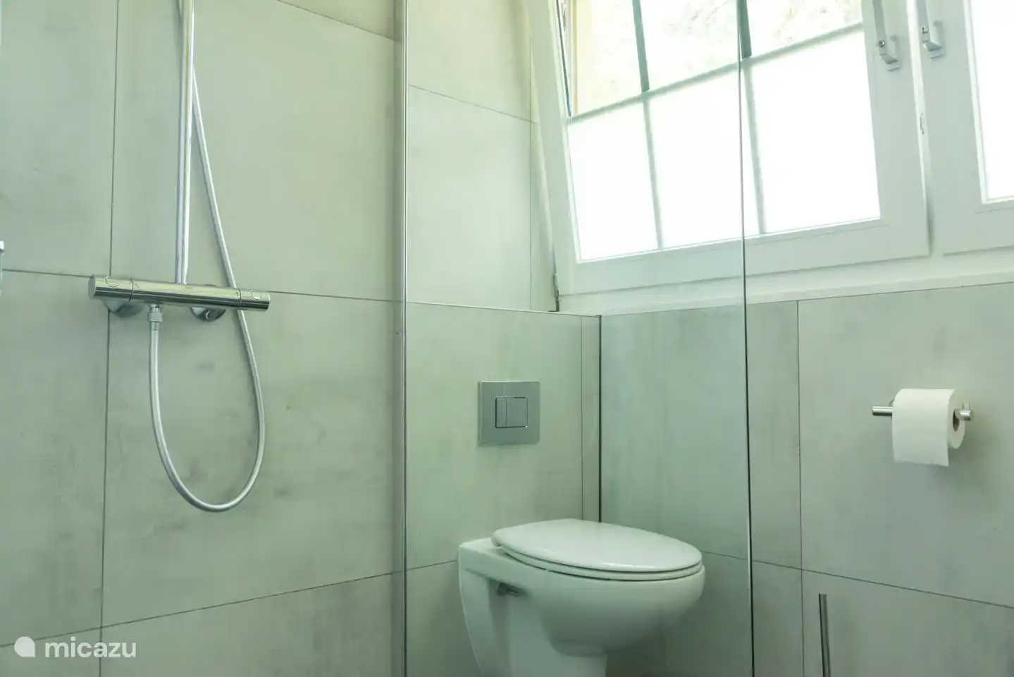 Badezimmer mit ebenerdiger Dusche, WC und Waschbecken im 1. Stock.