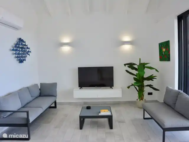Blue Bay Penthouse REEF 5 OCEAN VIEW huren in Curaçao, Curacao-Midden, Willemstad - appartement Woonkamer met Smart TV en 50 plus kanalen, airco unit en schuifdeuren naar terras van 30m2. aan de wanden local art