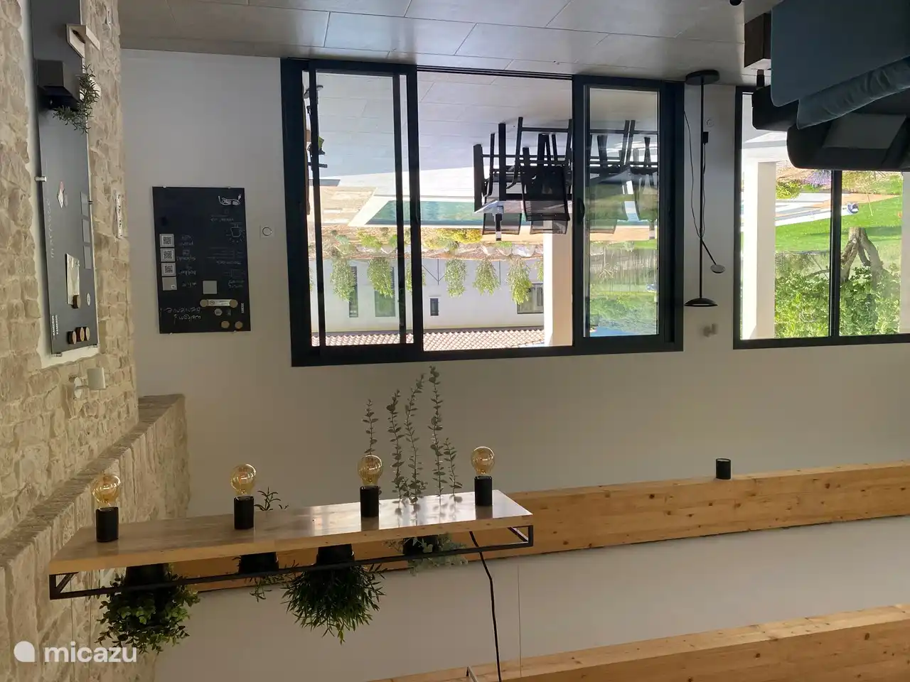 Das Wohnzimmer von der Küche mit Flügeltüren zur Terrasse mit Swimmingpool und der wachsenden Oleanderhecke