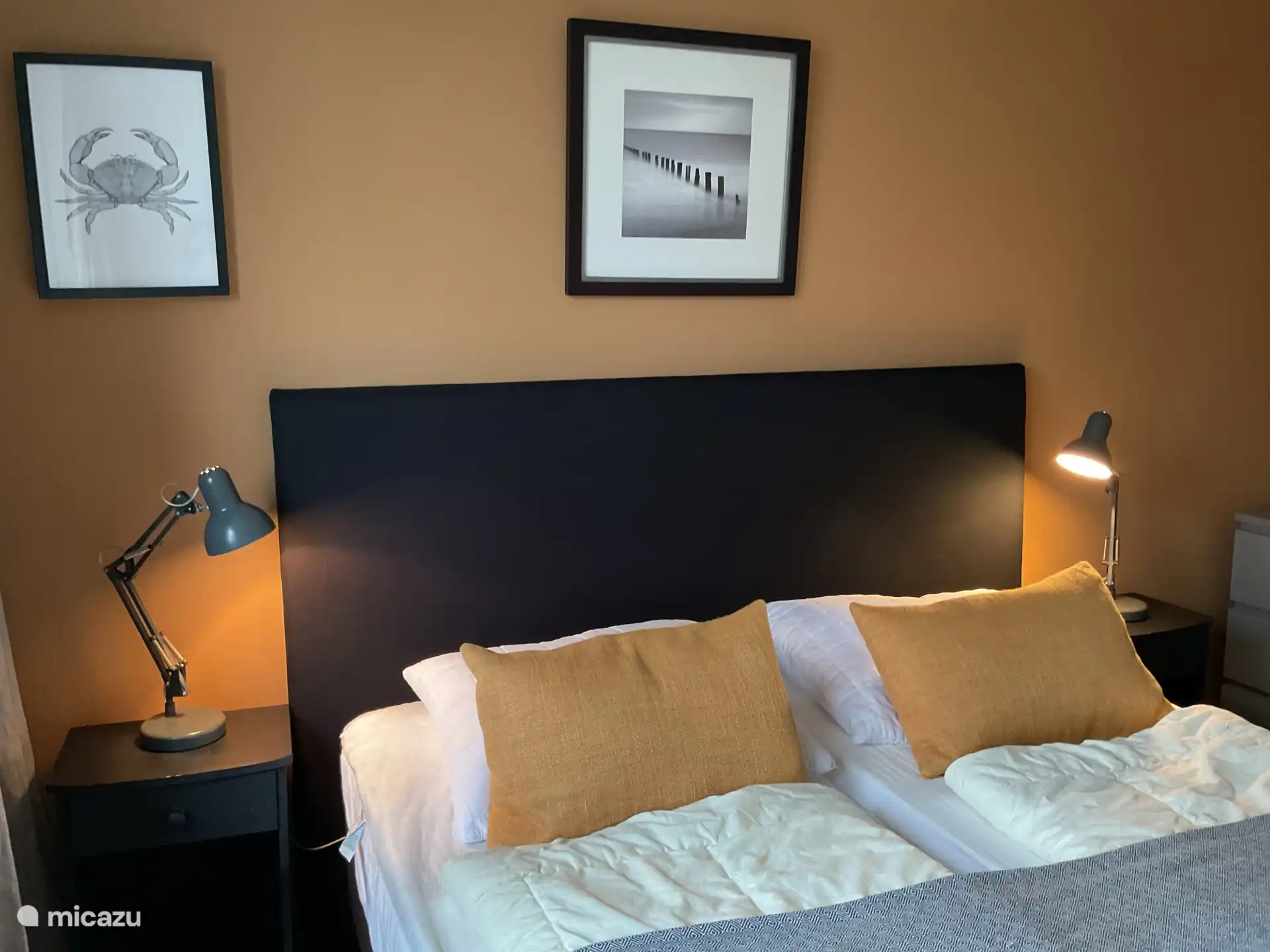 Een fijne, ruime en lichte eerste slaapkamer waar je echt tot rust komt, met warme kleurtinten en ramen voorzien van een vliegenhor.