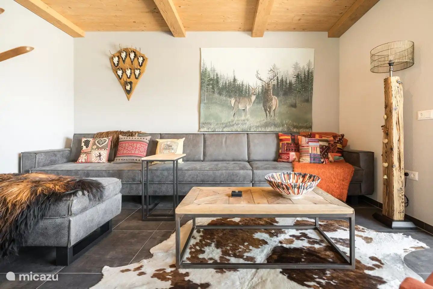 Salon avec grand canapé, pouf et télévision