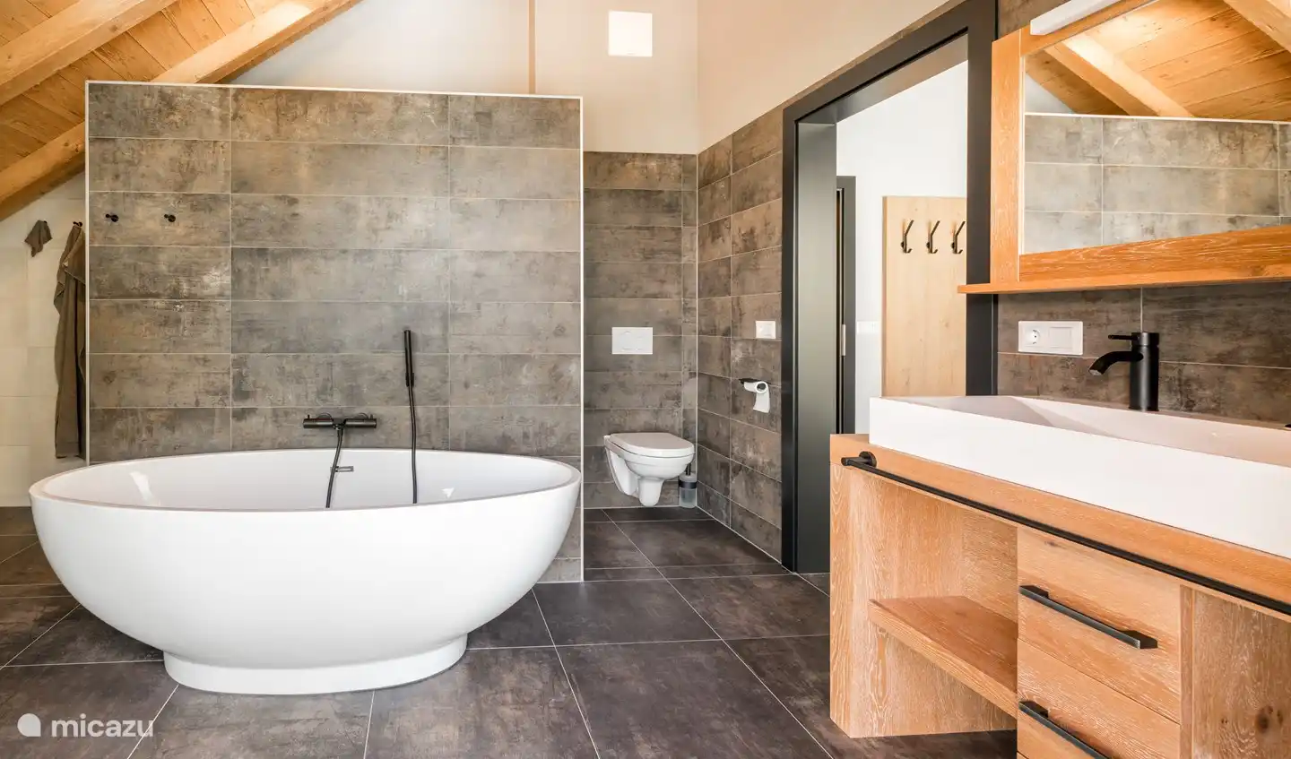 Salle de bain de luxe avec baignoire, douche à effet pluie, douchette, double vasque, toilettes et placards. Accès également à la chambre des maîtres et au balcon.