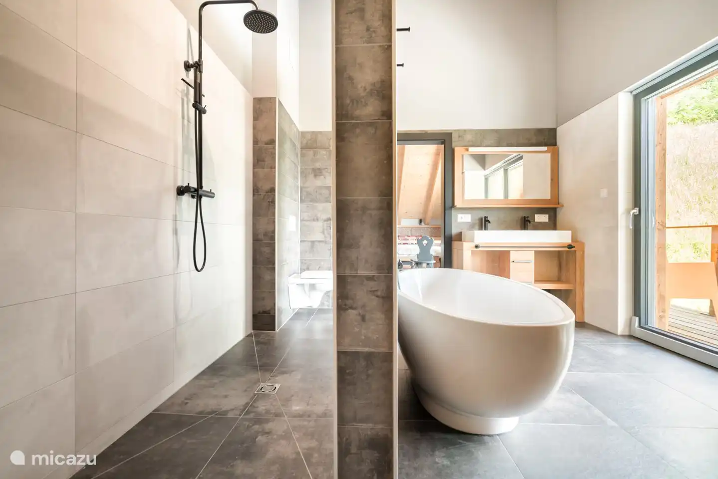 Salle de bain de luxe avec baignoire, douche à effet pluie, douchette, double vasque, toilettes et placards. Accès également à la chambre des maîtres et au balcon