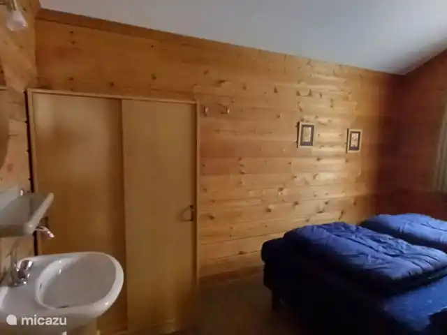 Chalet finlandais, dans un parc avec piscine | Pays-Bas, Overijssel, Gramsbergen - maison de vacances Chambre principale avec armoire coulissante, lavabo et chaise, 2 lits boxspring confortables avec lampes de chevet et tables de chevet