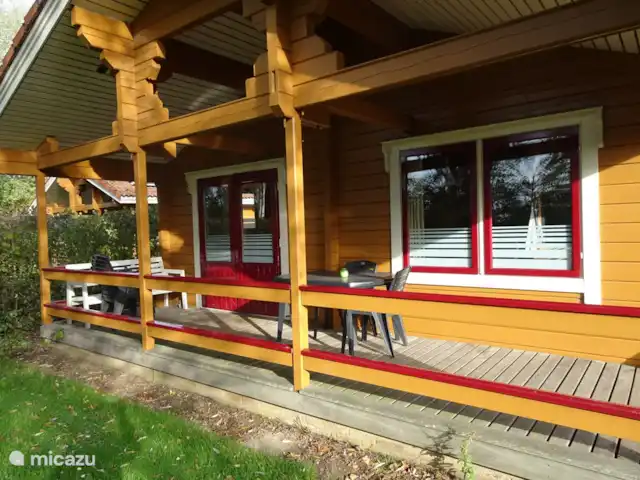 Chalet finlandais, dans un parc avec piscine | Pays-Bas, Overijssel, Gramsbergen - maison de vacances Véranda avec salon de jardin : table, 6 chaises et un canapé. Les oreillers se trouvent dans le placard supérieur de la chambre du milieu. 2 chaises longues se trouvent dans la chambre à côté du placard