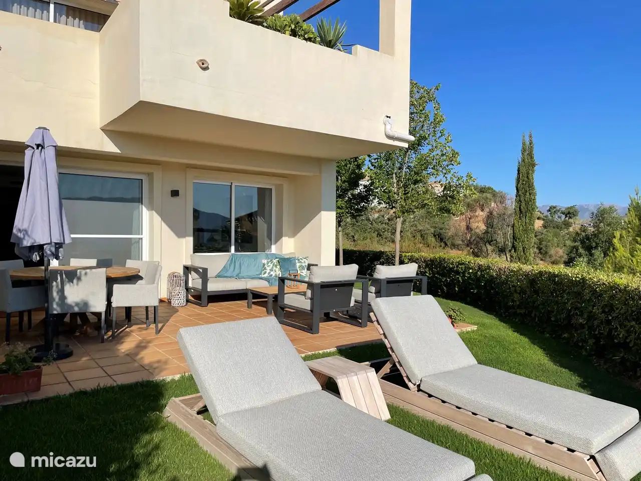 Precioso jardín con un fantástico juego de salón, tumbonas y un juego de comedor.