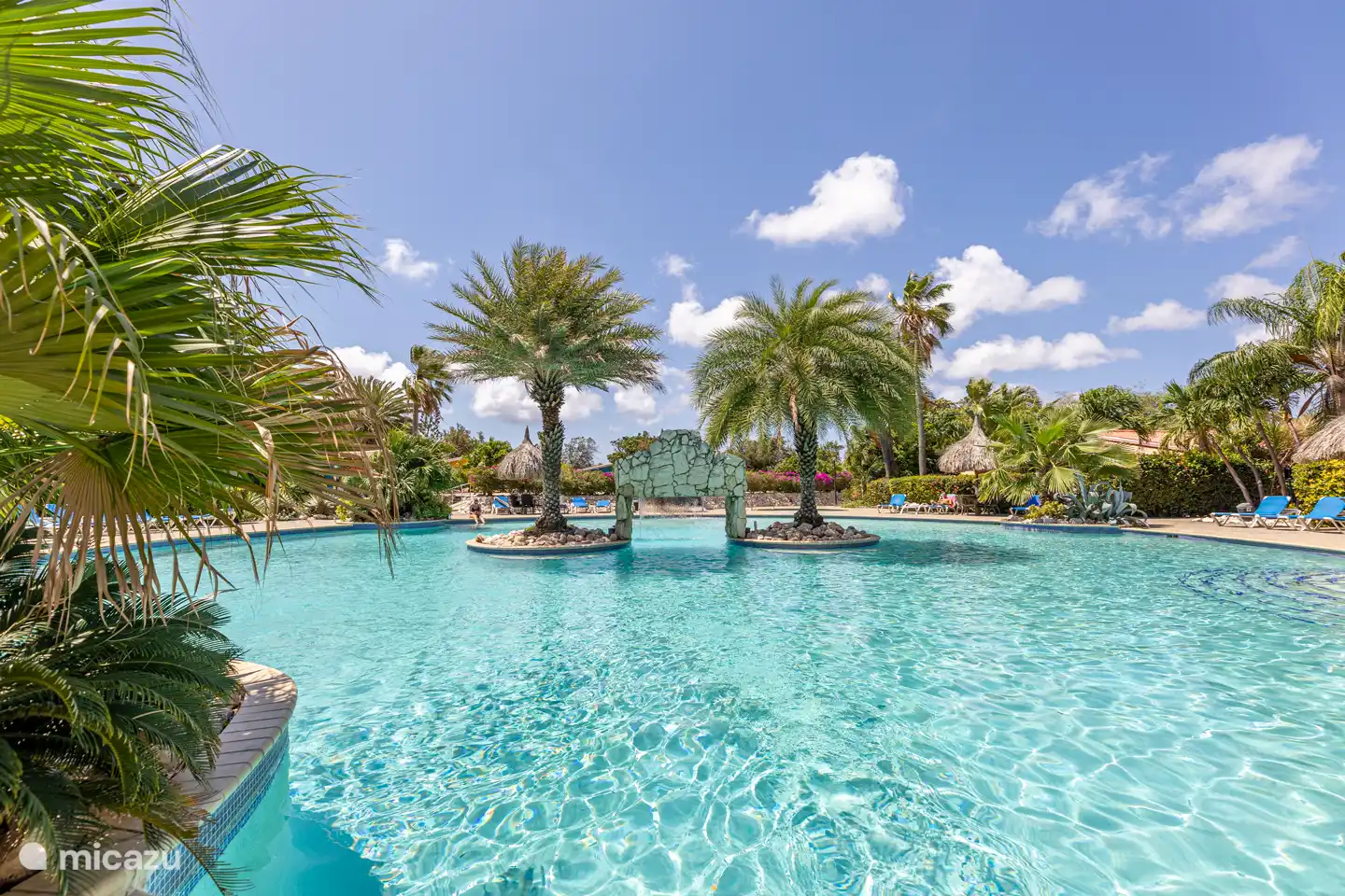 Piscina con muchas tumbonas y piscina infantil separada.