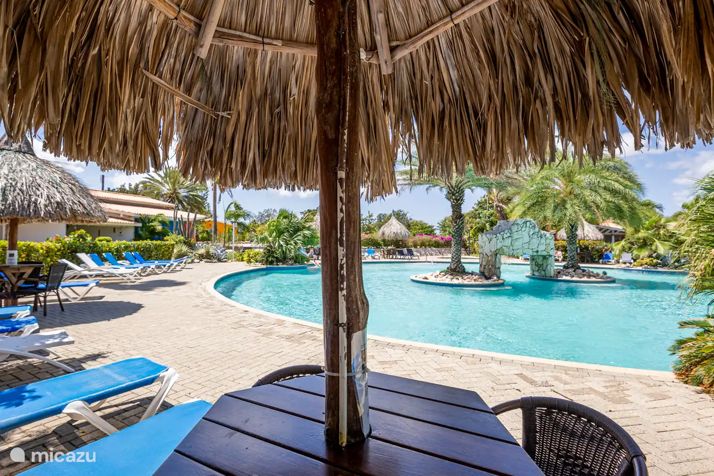 La piscina preciosa con muchas tumbonas y sombrillas.