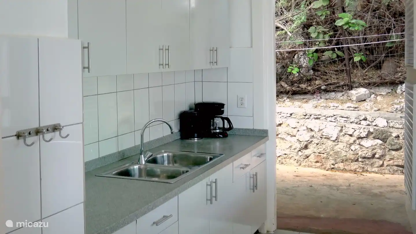 La cuisine s'ouvre sur le jardin de la terrasse arrière qui donne accès à la piscine, à la deuxième salle de bain extérieure et à la machine à laver.