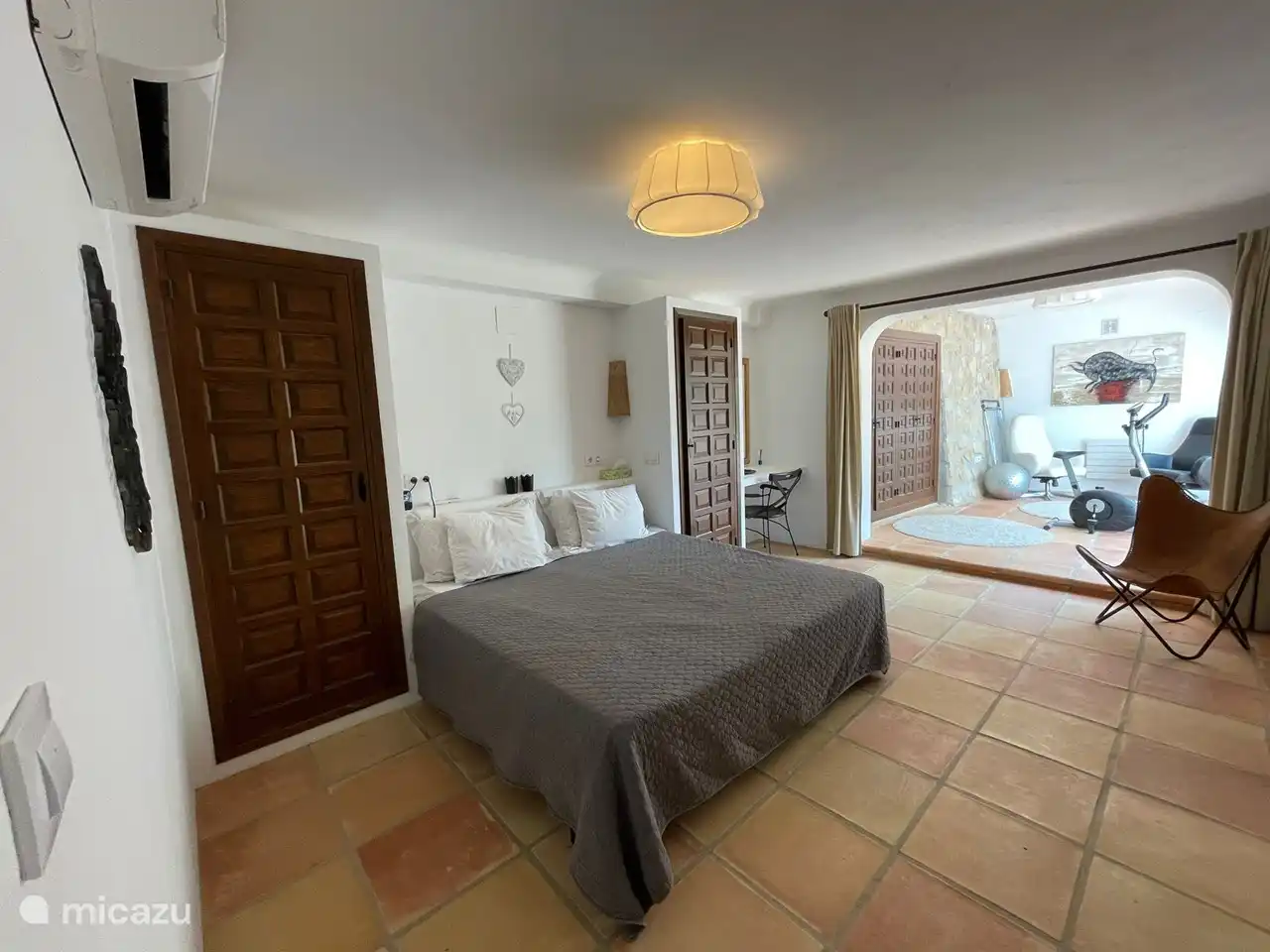 Chambre principale (au rez-de-chaussée) avec climatisation et ventilateur de plafond, salle de bain attenante, appareils de fitness (vélo d’appartement, stepper, trampoline et tapis roulant avec télévision), climatisation et ventilateur de plafond.
