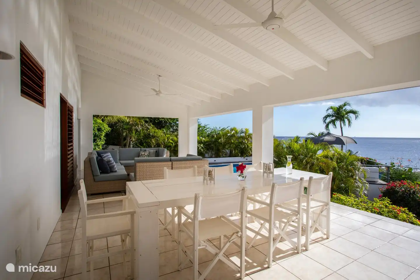Geräumige, schattige Veranda mit Sitz- und Essbereich und Meerblick.