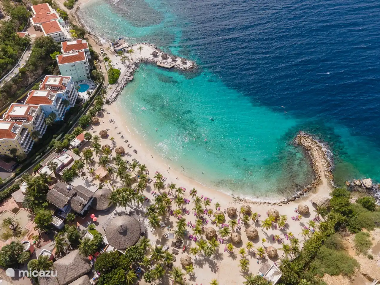 Plage avec une belle eau bleue, un bar, un restaurant de luxe et des mini-maisons exclusives avec vue sur l’eau