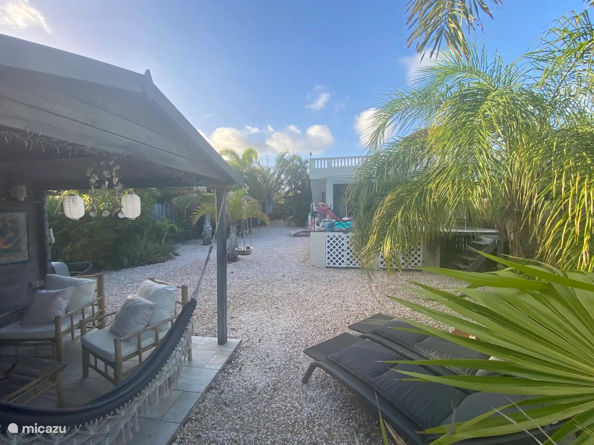 View of garden behind the house with pool, sunbeds, sitting area, parapa seating for six people and upper terrace with a view of Kralendijk and Klein Bonaire