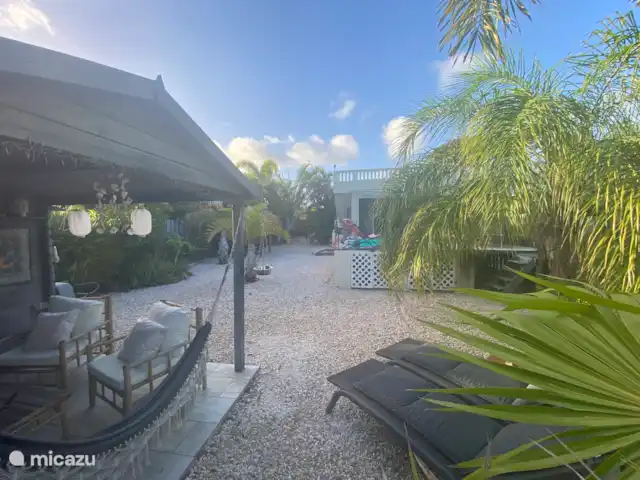 Domaine du Mile Bleu | Bonaire, Bonaire, Santa Barbara - maison de vacances Vue du jardin derrière la maison avec piscine, chaises longues, coin salon, parapa pour six personnes et terrasse supérieure avec vue sur Kralendijk et Klein Bonaire